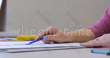 年轻的艺术家的手，女艺术家用石墨铅笔画画布，坐在桌子上画画布